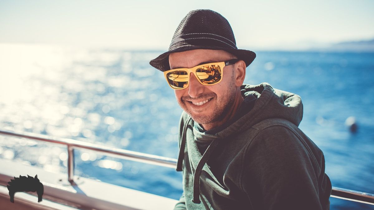 A man wearing sunglasses smiling near water.