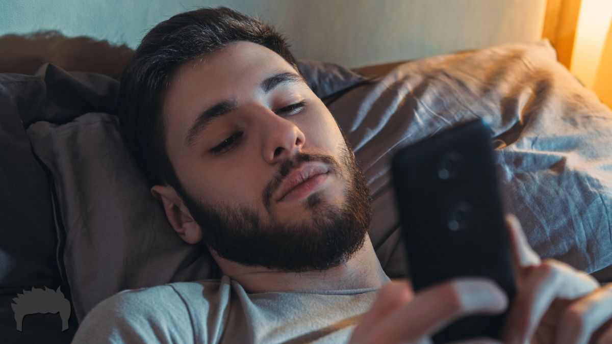 Man lying in bed on his phone.